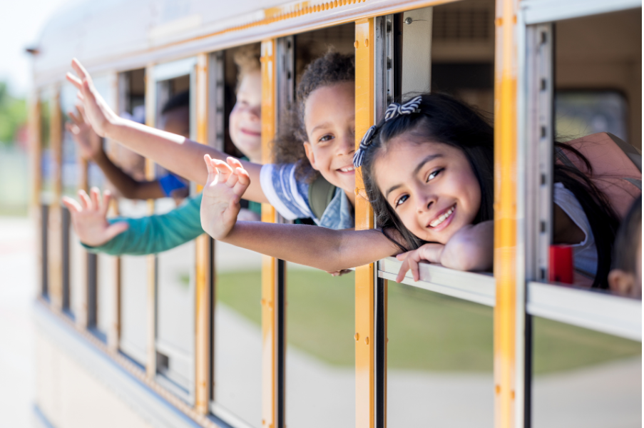 Children waving from a school bus window.